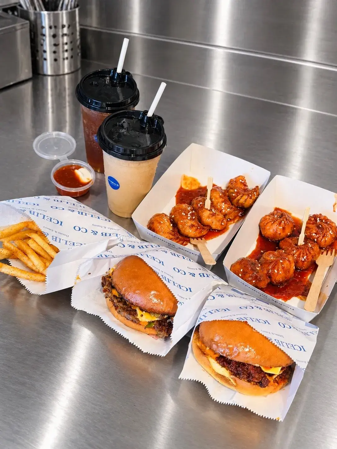 Smash burgers, glazed momos, fries and iced drinks on the steel counter