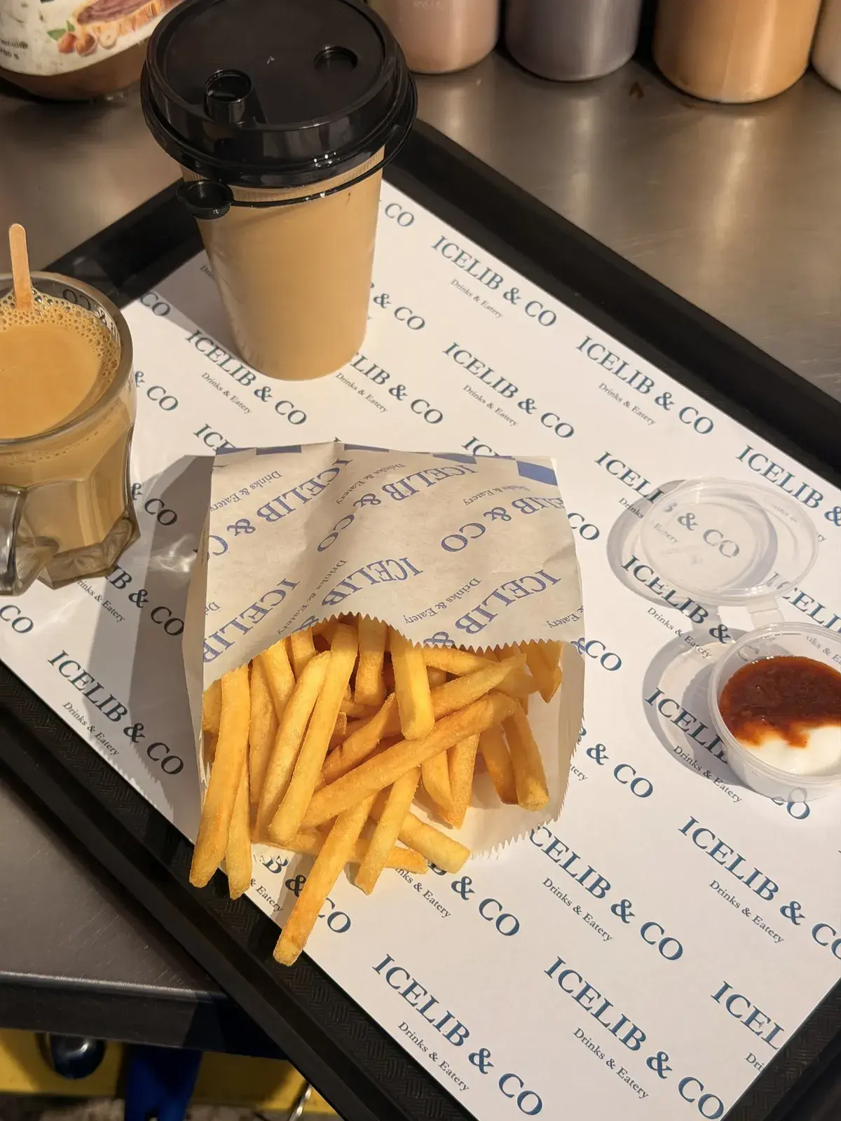 Fries in an Icelib & Co wrapper and an iced coffee on a branded tray
