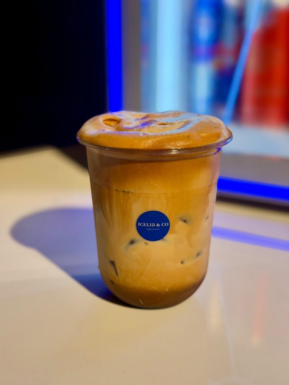 An iced coffee with a creamy foam top in an Icelib & Co cup on a café table