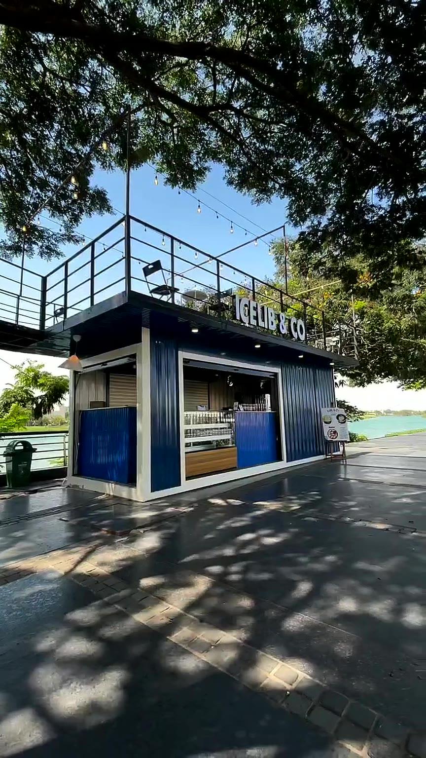 The blue Icelib & Co container under the trees by the lake on a sunny day