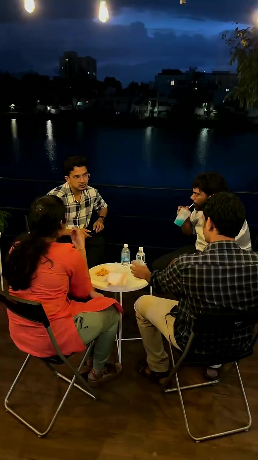 Guests at a table on the deck with the lake and city lights behind at night