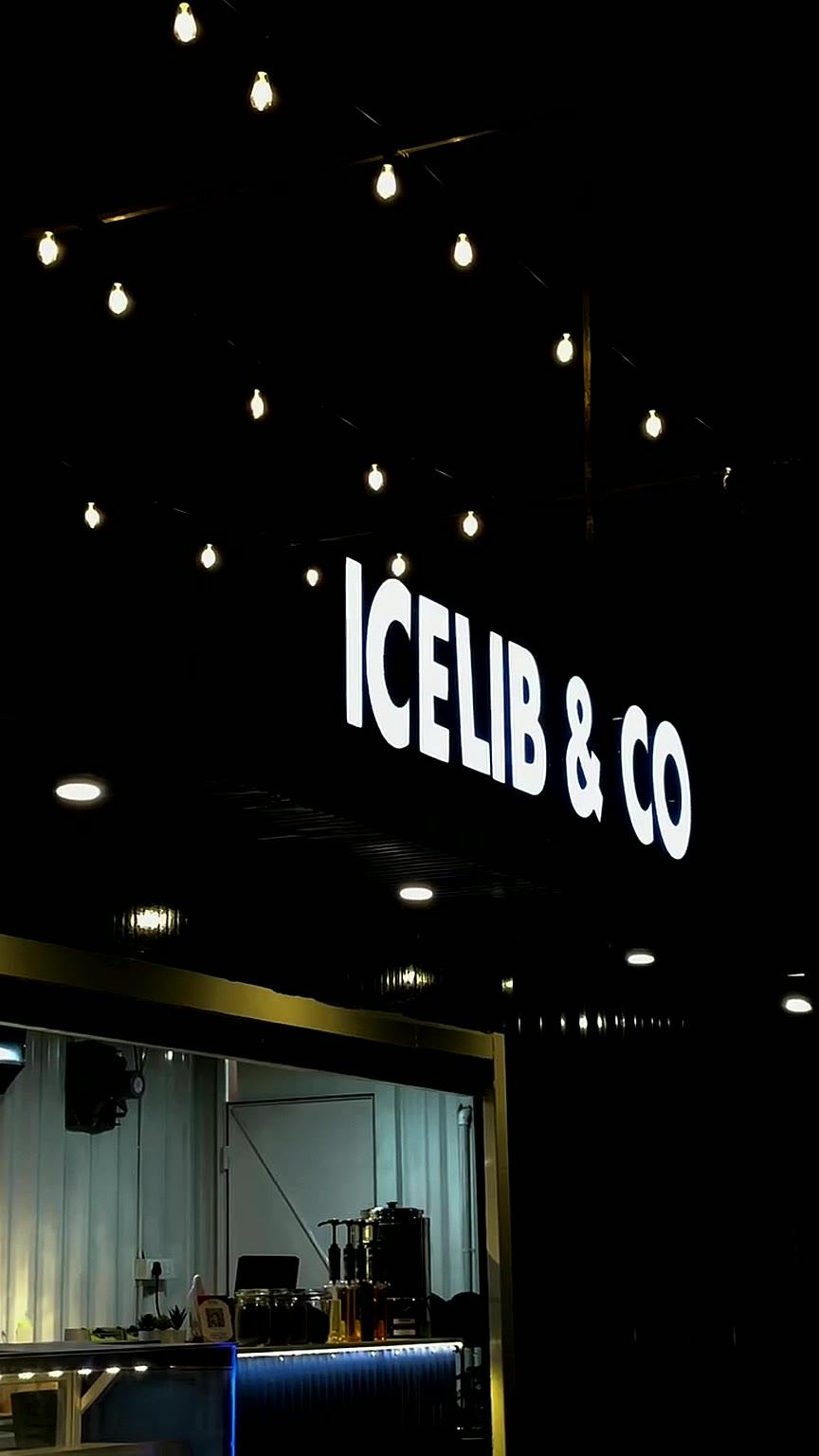 The glowing Icelib & Co sign and counter at night beneath string lights